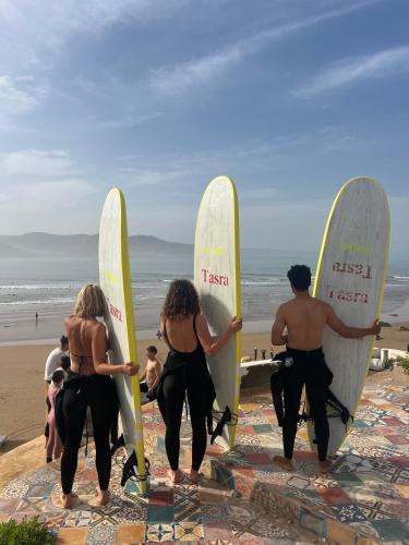 a group of people holding surfboards on the beach at Tasra Surf and Flow in Imsouane