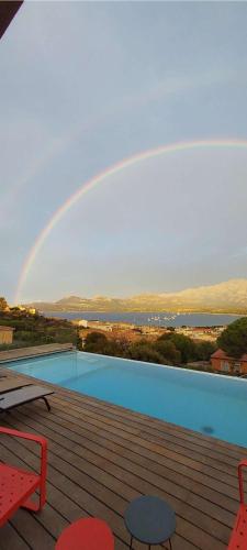 - un arc en ciel au-dessus d'une piscine dans l'établissement Villa avec vue panoramique sur la baie, à Calvi