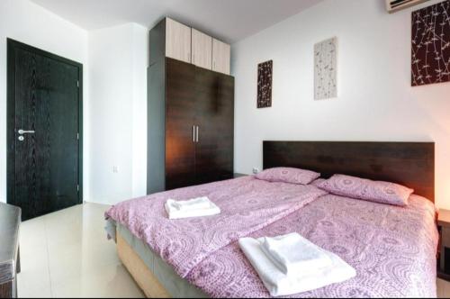a bedroom with a purple bed with two towels on it at Atlantis Getaway in Burgas City