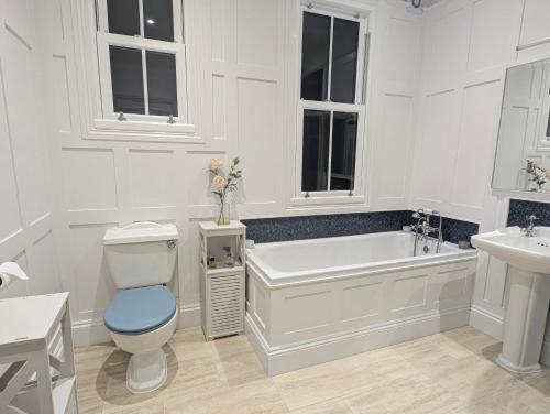 a white bathroom with a tub and a toilet and a sink at Mitton Villa in Stourport
