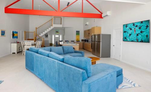 a living room with blue couches and a kitchen at Jolly Rancher Exuma 5 bed 6 bath multi family in Georgetown