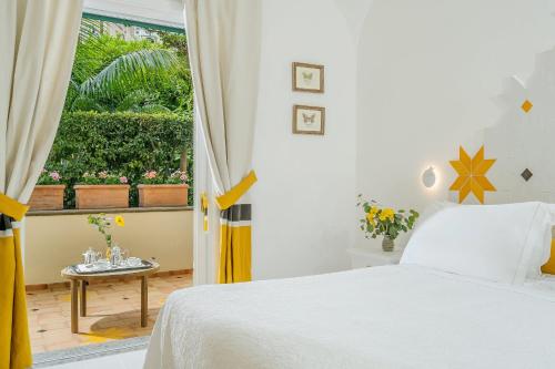 a white bedroom with a bed and a window at Hotel Palazzo Murat in Positano