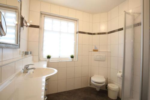 a white bathroom with a sink and a toilet at Wohnung Aurora im Haus Nautilus in Wangerooge