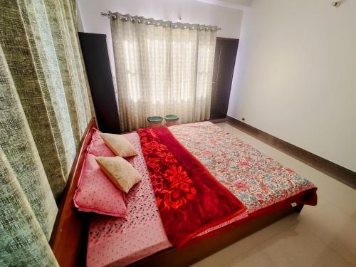 a bedroom with a bed with a red blanket and pillows at Whispering Meadows in Shimla