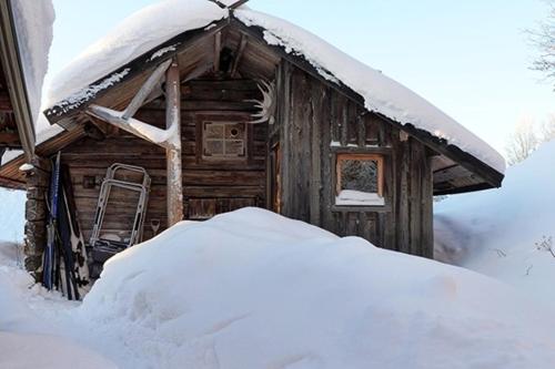 a snow covered cabin with a snow pile in front of it at Unigue mountain lodge in the heart of Jämtland in Undersåker