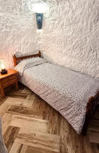 a bedroom with a bed and a table with a lamp at La Petite Chaouen de Galera in Galera