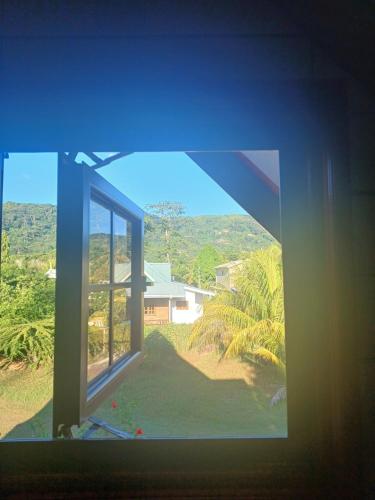 an open window with a view of a house at La Banane Rouge Self Catering in La Digue