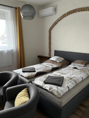 a bedroom with two beds and a chair and a window at Apartman - Garden - Vendégház in Nesvady