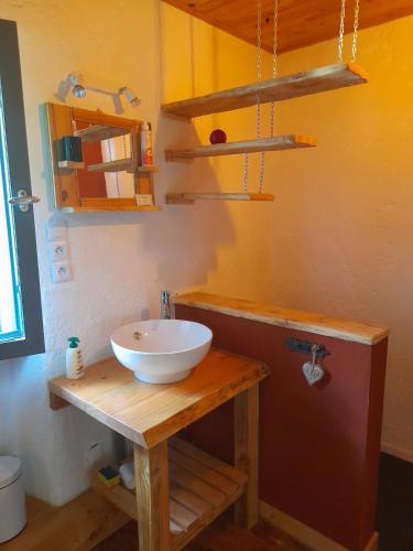 La salle de bains est pourvue d'un lavabo blanc sur une table en bois. dans l'établissement Gîte avec restaurant privatisé, à Biollet
