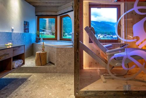 a bathroom with a tub and a chair next to a window at Hotel Spielmann in Ehrwald