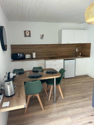 a kitchen with a wooden table and green chairs at Maisons Martigny C - Proche Futuroscope et Aquascope in Chasseneuil-du-Poitou