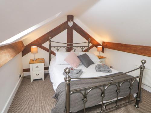 a bedroom with a bed with white sheets and pink pillows at Barnfields Holiday Cottage in Kingsley