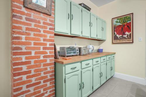 a kitchen with green cabinets and a brick wall at Maison des Reves - Historic charm in the heart of Downtown! in Cape Charles