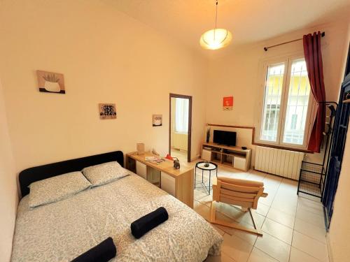une chambre avec un lit, un bureau et une télévision dans l'établissement Charmant T2 proche centre Nîmes, à Nîmes