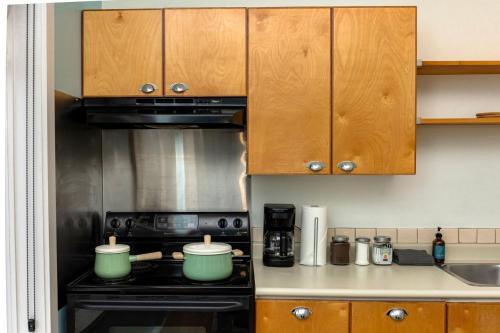 a kitchen with wooden cabinets and a stove top oven at Tofino Waterfront Condo in Tofino