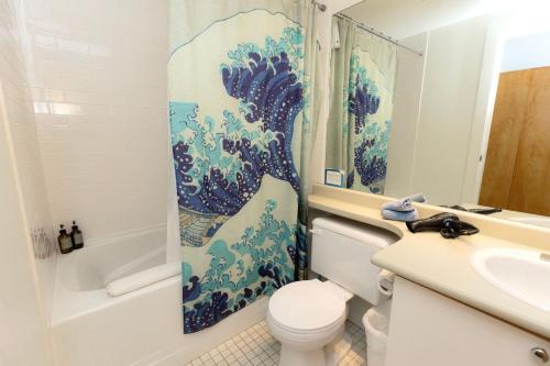 a bathroom with a toilet and a shower curtain at Tofino Waterfront Condo in Tofino