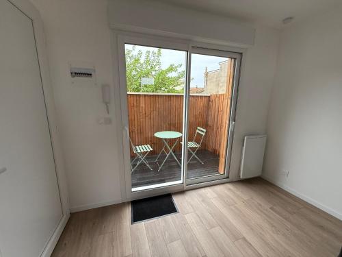 Cette chambre dispose d'une porte coulissante en verre avec une table et des chaises. dans l'établissement Julada Appartement, à Bègles