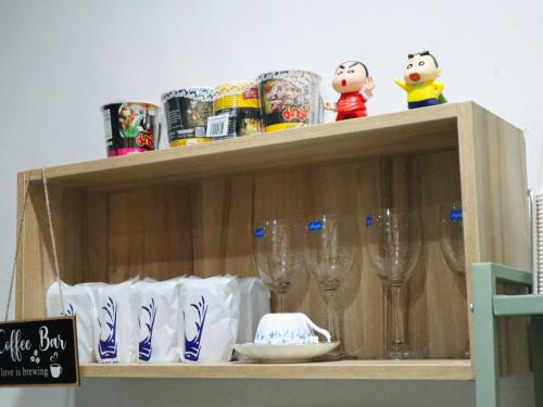 a shelf with wine glasses and other items on it at A Little Nap Hometel in Hat Yai
