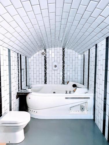 a white bathroom with a tub and a toilet at Ramsgate Seafront Apartment with Jacuzzi Bath & Pool Table in Ramsgate