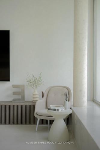 a white chair and a table in a room at Number Three Pool Villa Khaoyai in Ban Tha Maprang