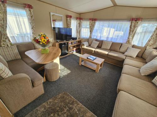 a living room with couches and a table and a tv at Hot Tub Getaways The Oakley 8 berth caravan with hot tub and quiet setting in Tattershall