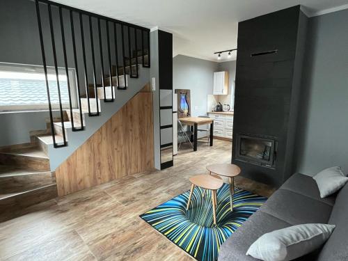 a living room with a staircase with a couch and a fireplace at Domki w Bieszczadach Kuźmina in Kuźmina
