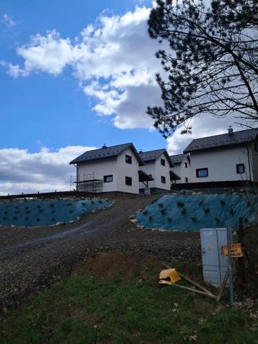 a couple of white buildings in a field at Domki w Bieszczadach Kuźmina in Kuźmina