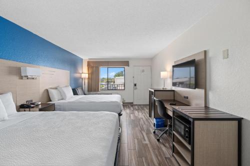 a hotel room with two beds and a desk at Baymont by Wyndham Orlando Downtown in Orlando