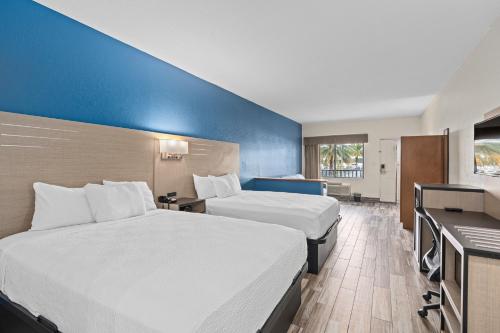 a hotel room with two beds and a desk at Baymont by Wyndham Orlando Downtown in Orlando