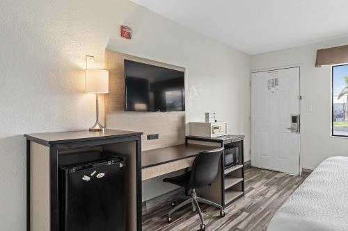 a hotel room with a desk and a bed and a chair at Baymont by Wyndham Orlando Downtown in Orlando