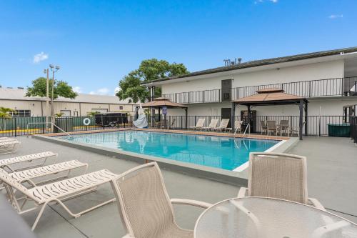 a pool with chairs and tables and a building at Baymont by Wyndham Orlando Downtown in Orlando