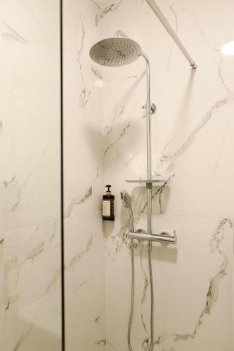 een douche in een badkamer met witte marmeren muren bij Apartment 103 in Tirana