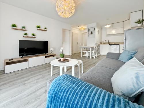 un salon avec un canapé, une télévision et une table dans l'établissement Sunny Suite Disneyland Paris - Rentaway BnB, à Montévrain