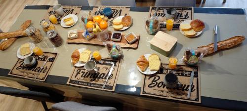 een tafel met een heleboel verschillende soorten voedsel erop bij Le Jardin des 2 Cèdres in Isigny-le-Buat