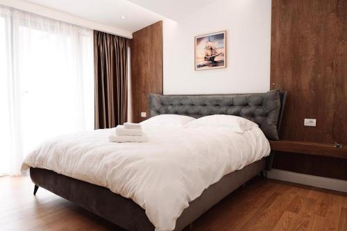 een slaapkamer met een groot bed met witte lakens bij Apartment 103 in Tirana