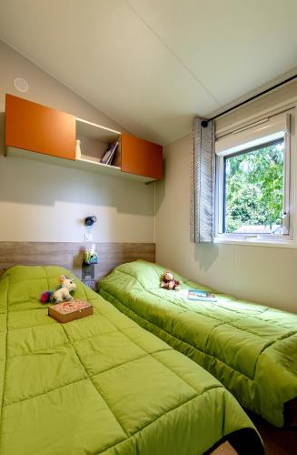 deux lits dans une chambre avec des draps verts dans l'établissement Mobil-home Confort 2 chambres avec lave-vaisselle, à Pordic
