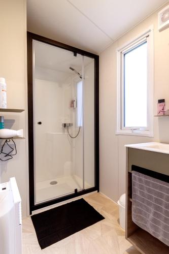 une salle de bain avec une douche avec une porte vitrée dans l'établissement Mobil-home Confort 2 chambres avec lave-vaisselle, à Pordic