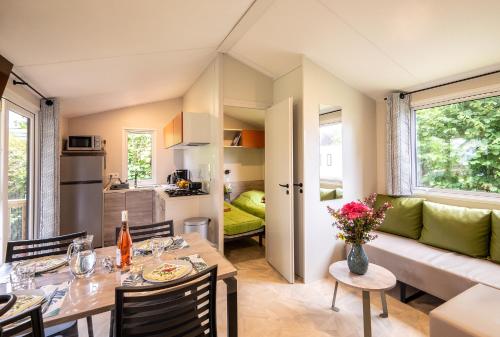 un salon avec une table et un canapé dans l'établissement Mobil-home Confort 2 chambres avec lave-vaisselle, à Pordic