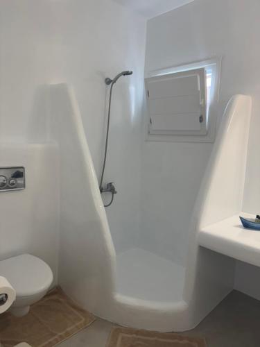 a white bathroom with a toilet and a lamp at Sakas Residences in Karterados
