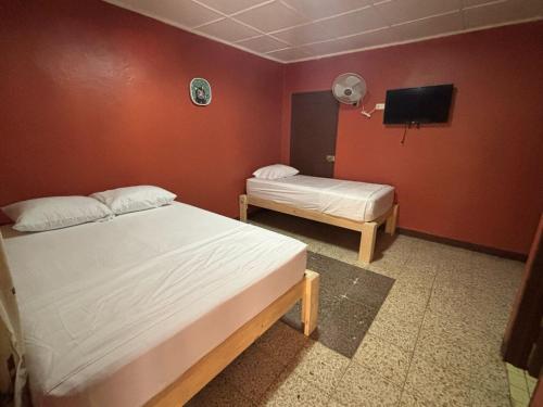 a room with two beds and a tv on the wall at Hotel Rio Mar in Puntarenas