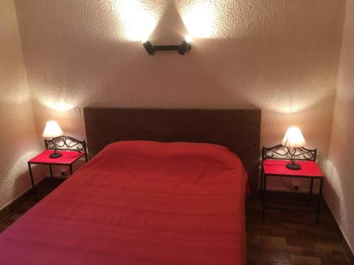 - une chambre avec un lit rouge et deux lampes de chaque côté dans l'établissement RESIDENCE PLAGE ET MAQUIS, à Solaro