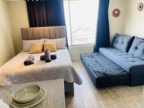 a living room with a bed and a blue couch at 17 Apartamento en Santiago en frente a Metro - Estadio - Hipodromo de Chile in Santiago