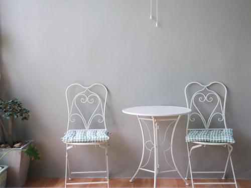 two chairs and a table in front of a wall at A Little Nap Hometel in Hat Yai