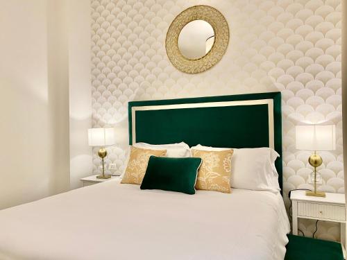 a white bed with a green headboard and a mirror at Mazzini 34 Collection in Florence
