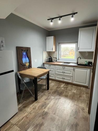 a kitchen with a wooden table and a refrigerator at Domki w Bieszczadach Kuźmina in Kuźmina
