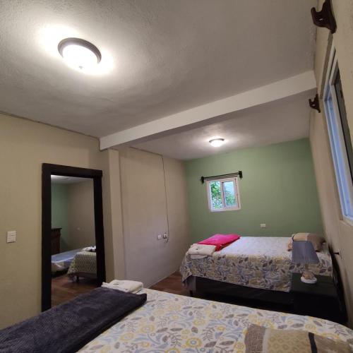 a bedroom with two beds and a mirror at Volcano Tours, Fuego y Acatenango in Yepocapa