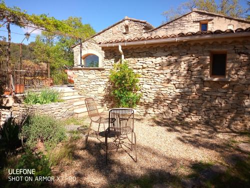 une maison en pierre avec deux chaises devant elle dans l'établissement La maison jaune, à La Roque-sur-Pernes
