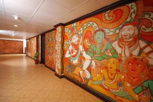 a large mural in a hallway with paintings on the wall at The Raviz Kadavu, Kozhikode in Kozhikode