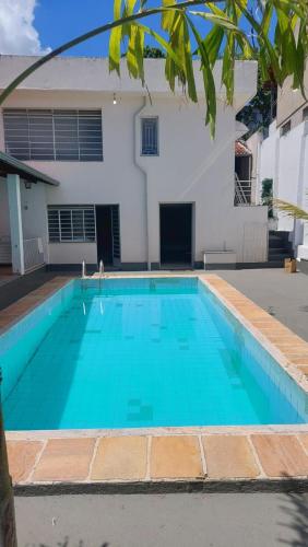 a swimming pool with blue water in front of a house at Casa em Belo Horizonte - Pampulha in Belo Horizonte