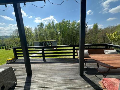 a wooden deck with a table and a bench at OdpocznieszTU in Brzozowa